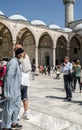 pilgrims and tourists in the courtyard of the Blue Mosque, historic mosque located in Istanbul, Turkey. A popular tourist site